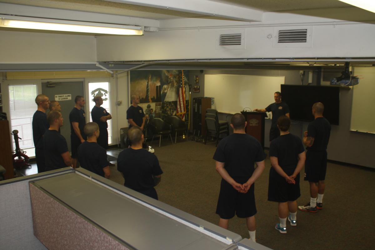 Hayward Fire Department recruits stand in a circle in a training classroom