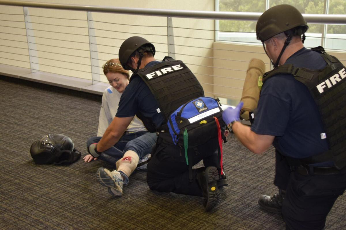 Fire fighters in tactical gear work on a fake victim's leg wound