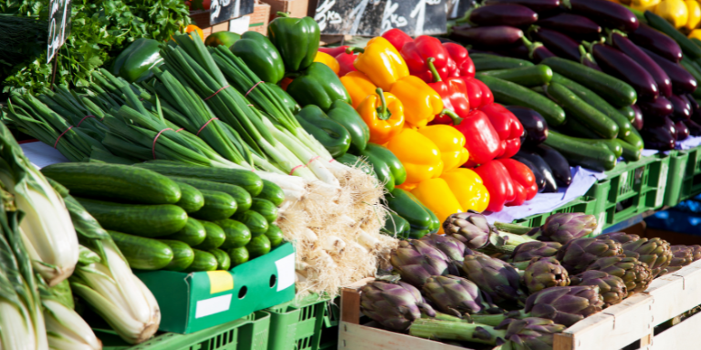 Photo of a stand full of colorful vegetables at a farmers market.