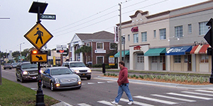 A man walking in a crosswalk with flashing beacons