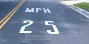 White lettering on a black top road: MPH 25