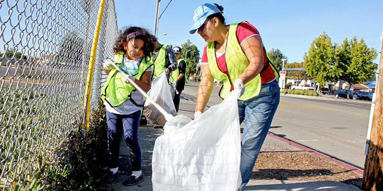 a woman and a child picking up trash 