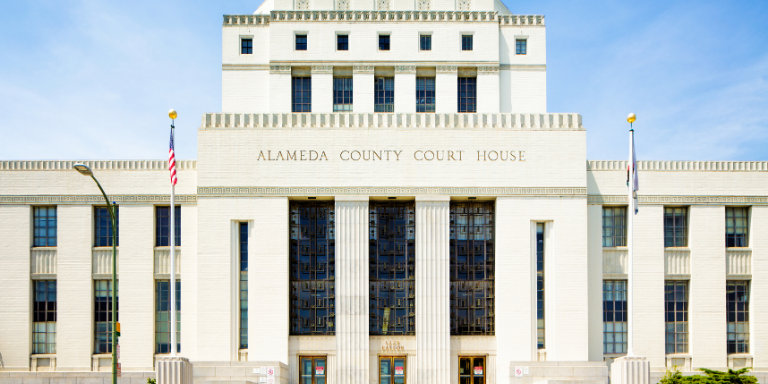 Photo of the Alameda County Court House, a large, white, and rectangular government building.