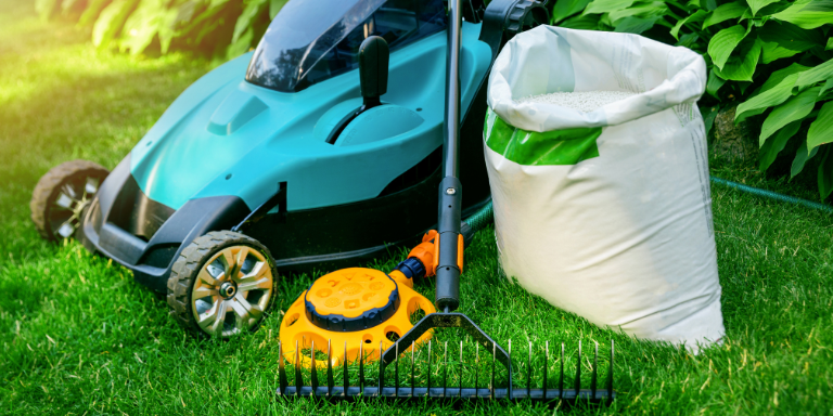 Photo of a lawn mower, a bag, and a rake.