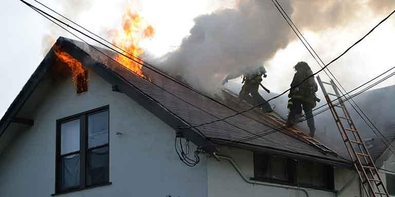 Fire fighters putting out a fire on a house roof