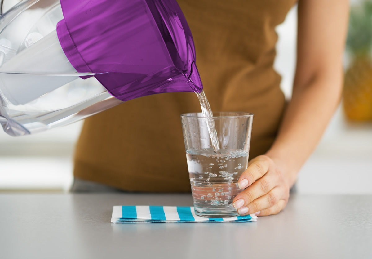 Woman pour water from a clear pitcher into a glass