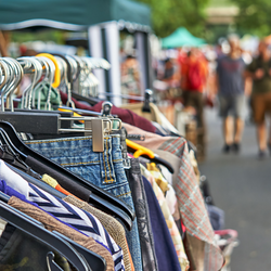 Photo of a flea market with clothes on a rack in focus while the rest of the background is blurry.