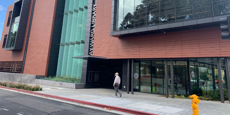 A person walking in front of the Downtown Hayward Library