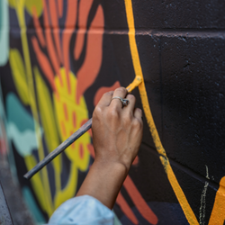 Hand painting a line as part of a mural on the wall.