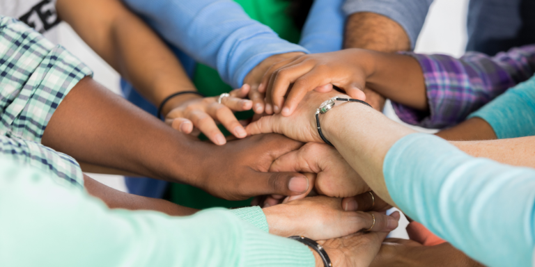 A group of people with their hands in a pile