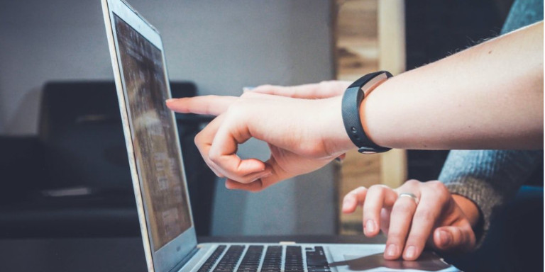 A laptop computer and the hands of a teacher and a learner 