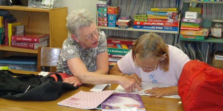 A tutor and an adult student reading together