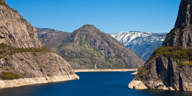 Photo of Hetch Hetchy reservoir. A large blue body of water surrounded by mountains.