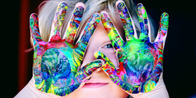 A child with multi-colored paint on their hands