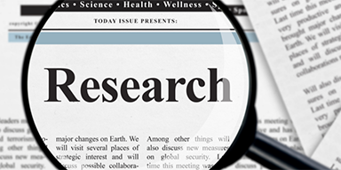 A newspaper with a magnifying glass focused on the word Research