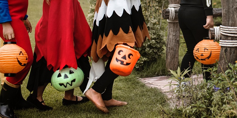 Children trick or treating during the day in brightly colored costumes