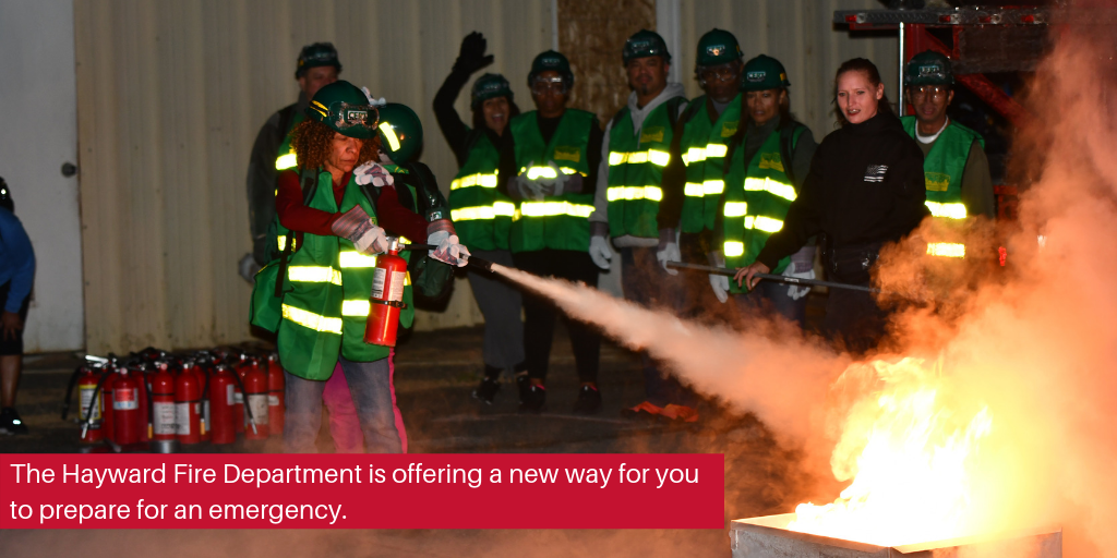 A group of people in green vests watching a women put out a fire