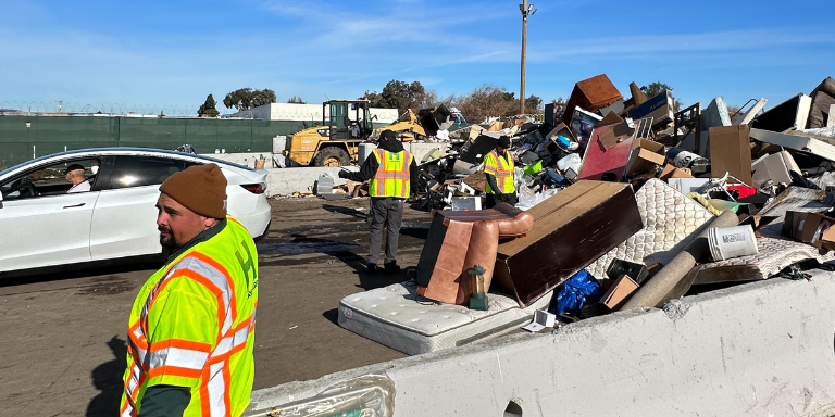 Photo of a person leaving their items to be disposed while City workers assist.
