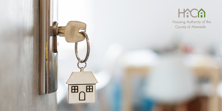 Photo of a key in the lock of a front door with a keychain hanging off of it.