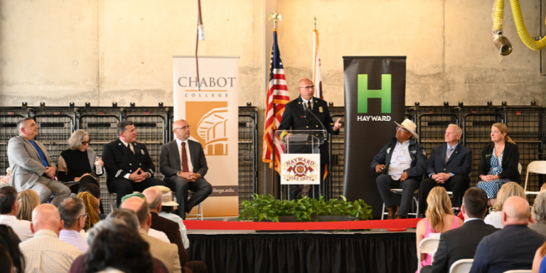 Photo of Fire Chief Garrett Contreras on a stage with other people talking to a crowd.