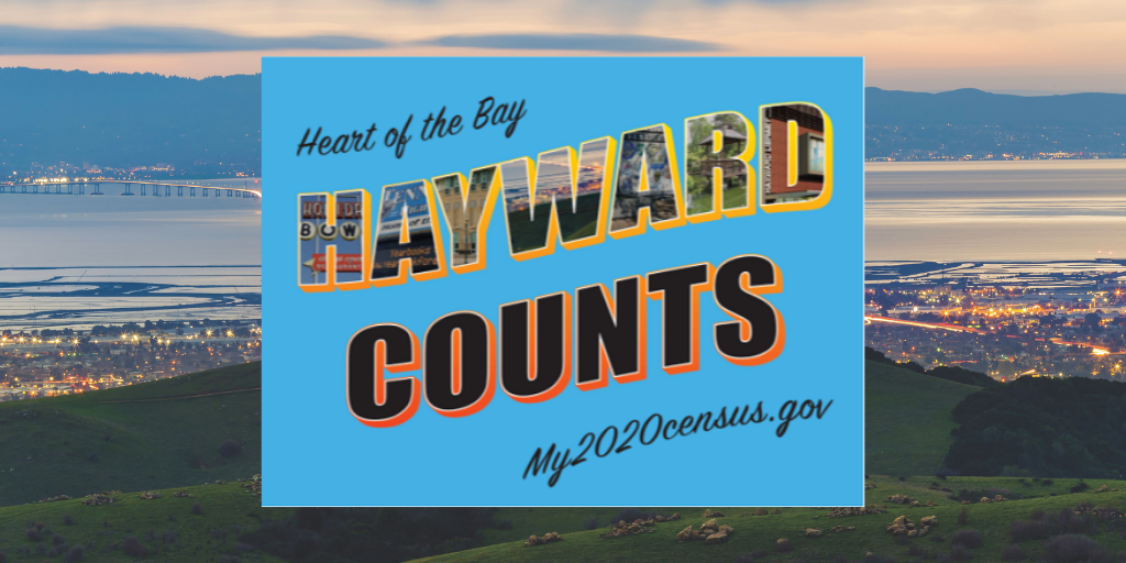 A blue Hayward Counts 2020 Census sign on top of a image of the Hayward skyline