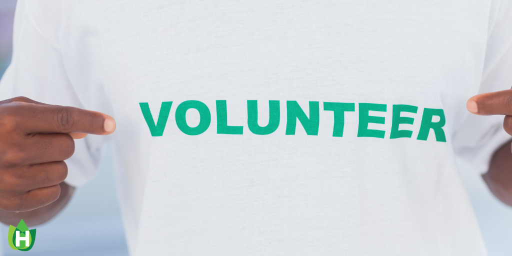 A person wearing a white shirt with the green word volunteer across their chest