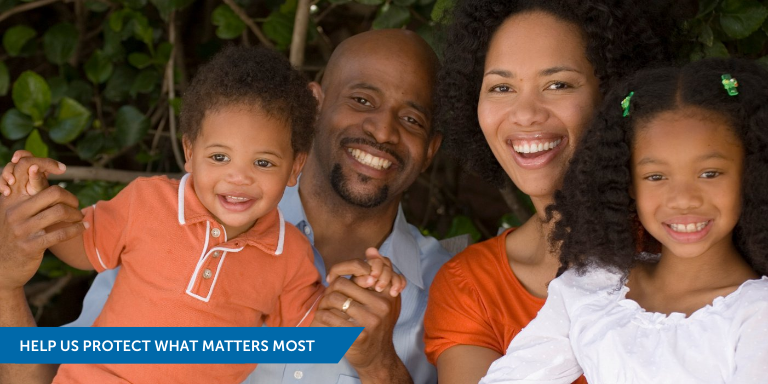 A smiling Black family posed for a photo including: a mother, father, daughter, and son.