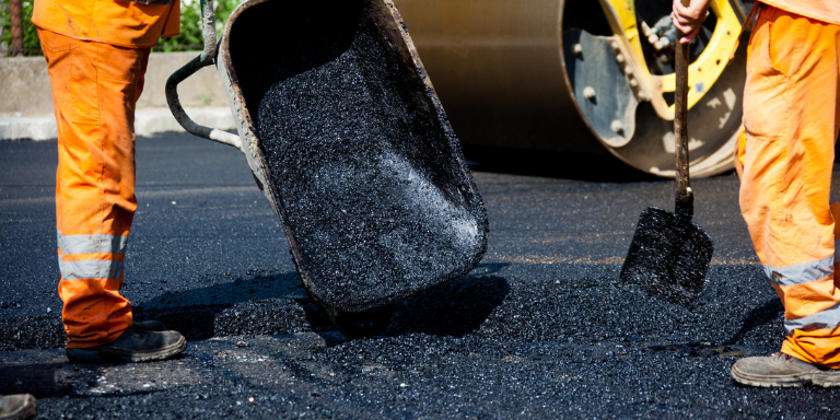 Two construction workers paving roads