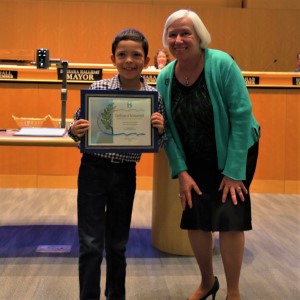 Young boy with a blue and white dress shirt standing with Mayor Halliday