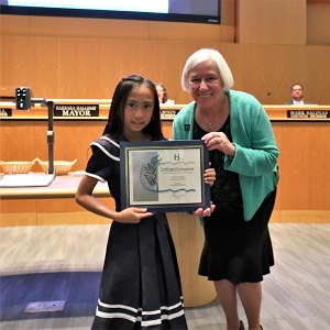 Little girl in a navy and white dress standing with Mayor Halliday