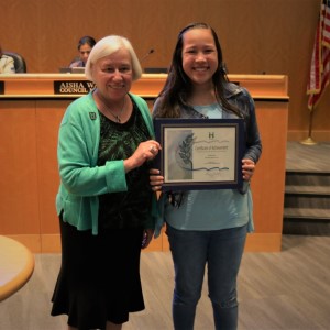 Young girl in a blue blouse and black jacket standing with Mayor Halliday