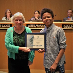 Young boy in a black and gray shirt standing with Mayor Halliday