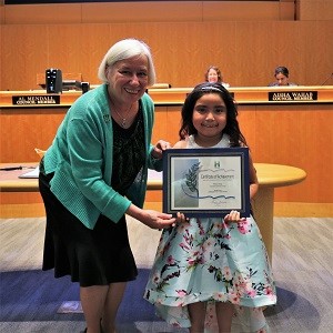 Little girl with a white and blue dress standing with Mayor Halliday