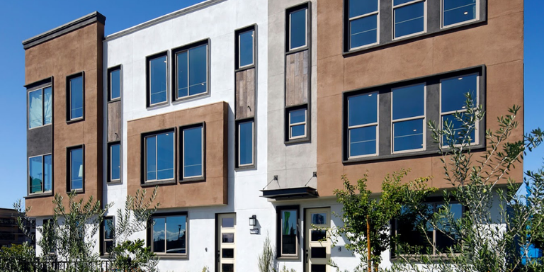 Photo of the Mission Crossings Apartment building a brown and white building with a lot of windows.