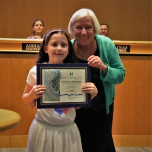 Little girl in a long white dress standing with Mayor Halliday