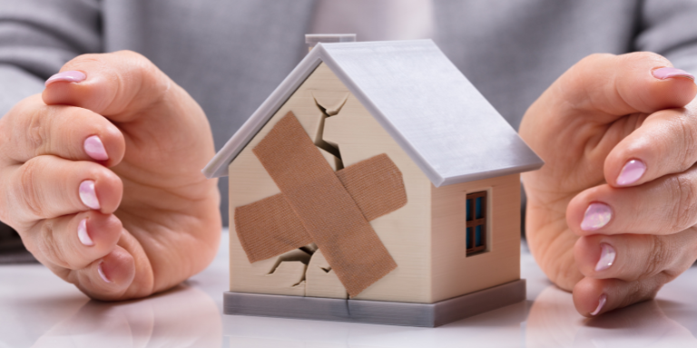 Hands around a broken house figurine.