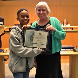 Young boy in a gray sweater standing with Mayor Halliday