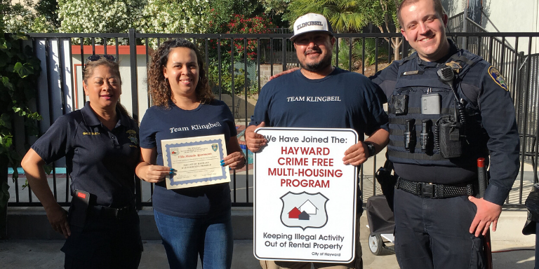 people standing with a crime free multi housing sign