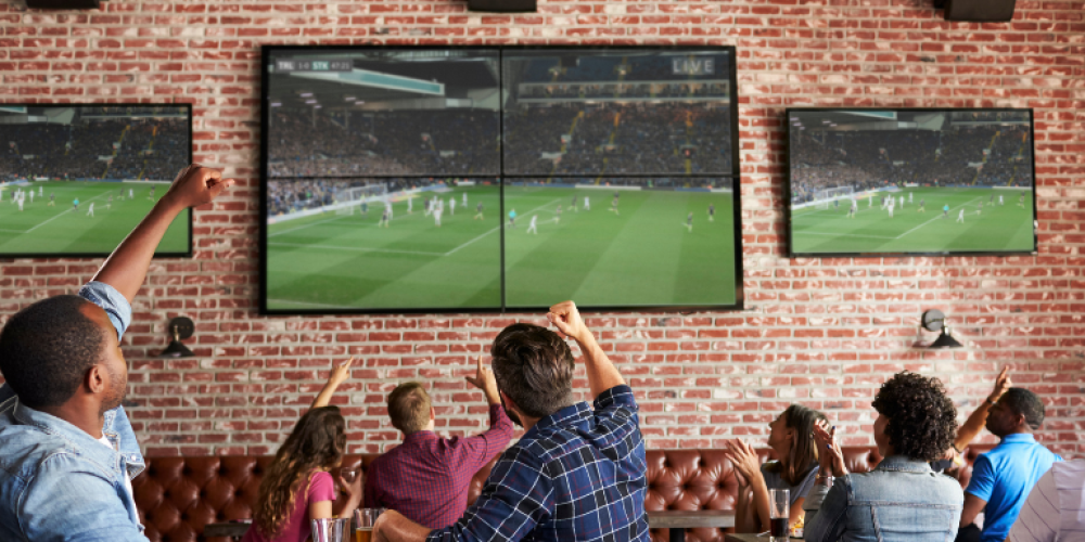 A group of people watching a soccer game at a restaurant 