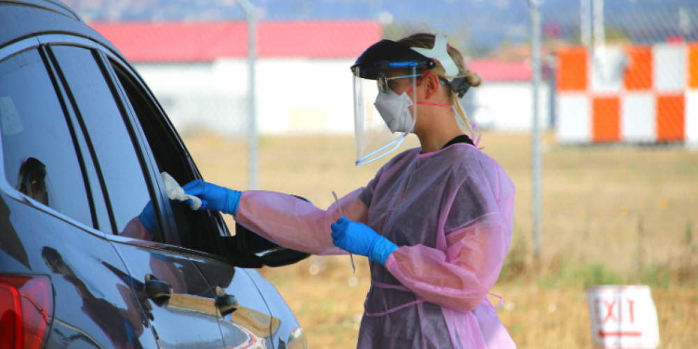 A woman in pink and blue protective gear talking to someone in a black SUV at the Testing Center Site at Skywest Golf Course