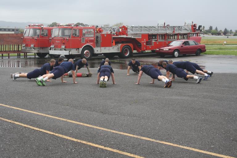 Hayward Fire Department recruits plank in front of two fire engines