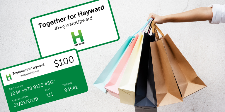 A person holding several shopping bags next to the Hayward giftcards