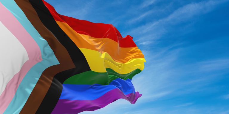 Image of Pride Flag against a blue sky.