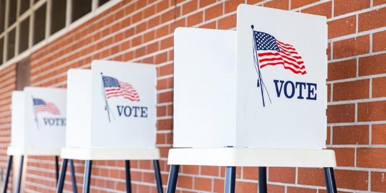 Photo of voting stands against a brick wall.