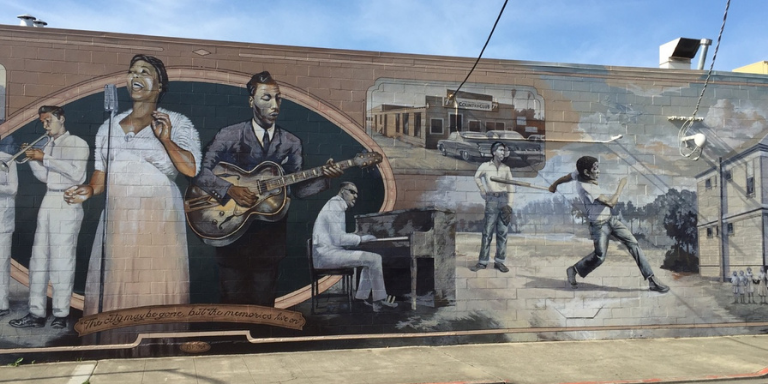 Russell City mural with painting of Jazz singers and performers as well as a little Black boy dancing.