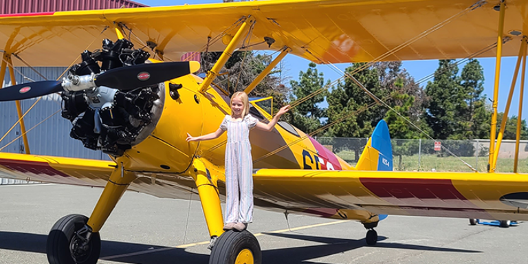 Photo of a girl posing on a propeller plane.